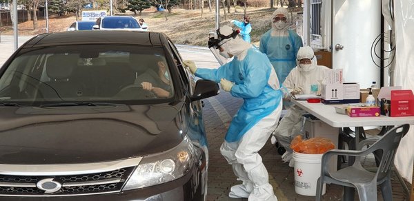 Южнокореец дава проба за коронавирус в една от мобилните станции в страната. Шофьорите могат да бъдат тествани без да слизат от колите си.jpg